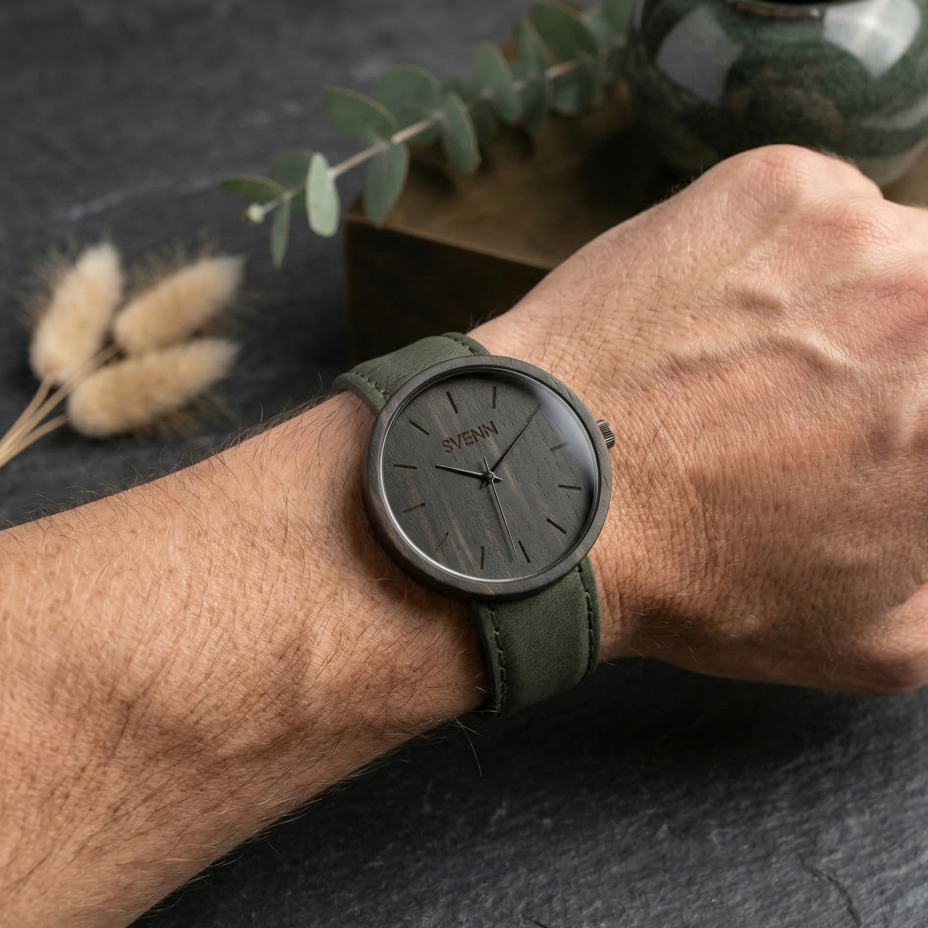 Erkek bileğinde doğal, ağırbaşlı ve premium bir duruş sergileyen, pürüzsüz abanoz ağacından üretilmiş özel bir hediye Svenn Ahşap Saat.